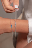 Woman wearing two 925 sterling silver zircon chain bracelets with blue and clear stones