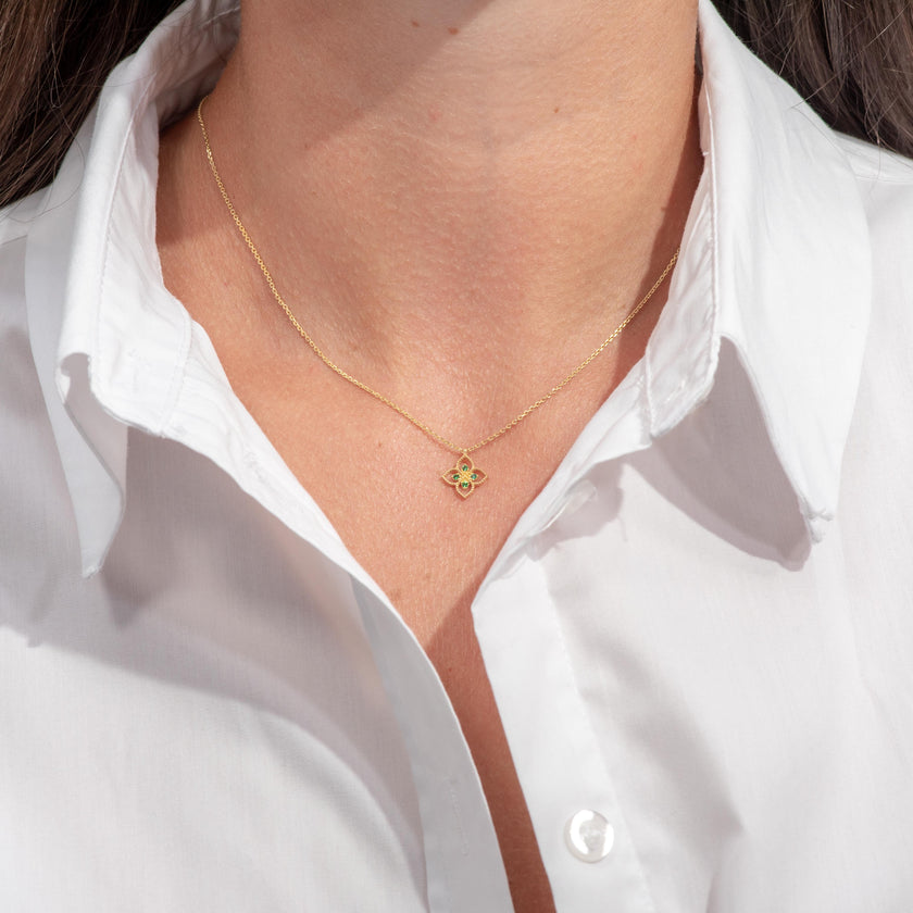 Woman wearing gold-plated 925 sterling silver pendant necklace with flower-shaped motif and green zircon stones